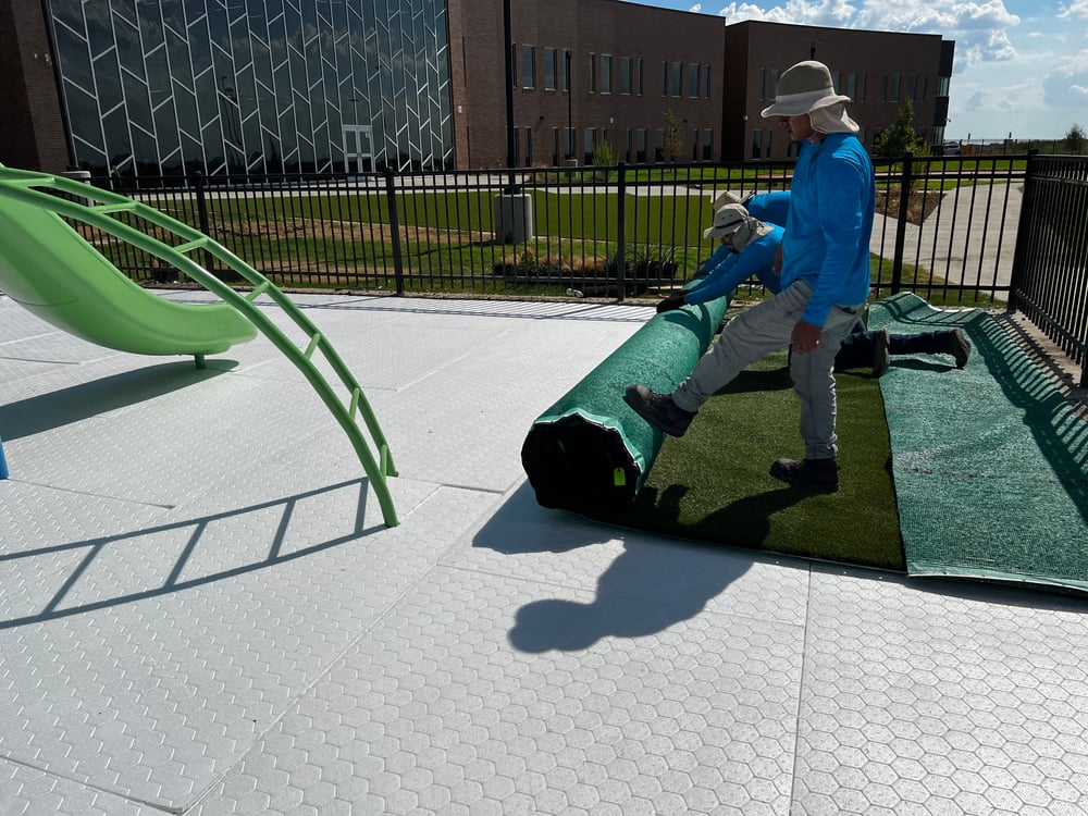 men roll out artificial turf onto Brock Pad